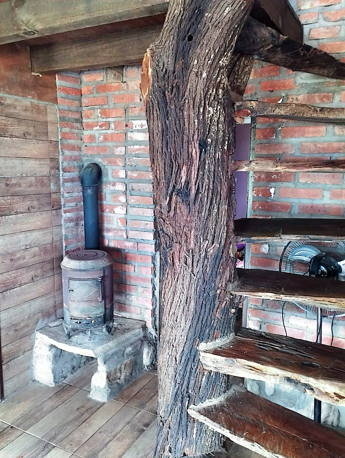 Interior de Mate Luna con estufa a leña y una columna de tronco