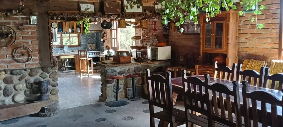 Quincho comedor de ladrillo y piedra con la mesa larga de algarrobo