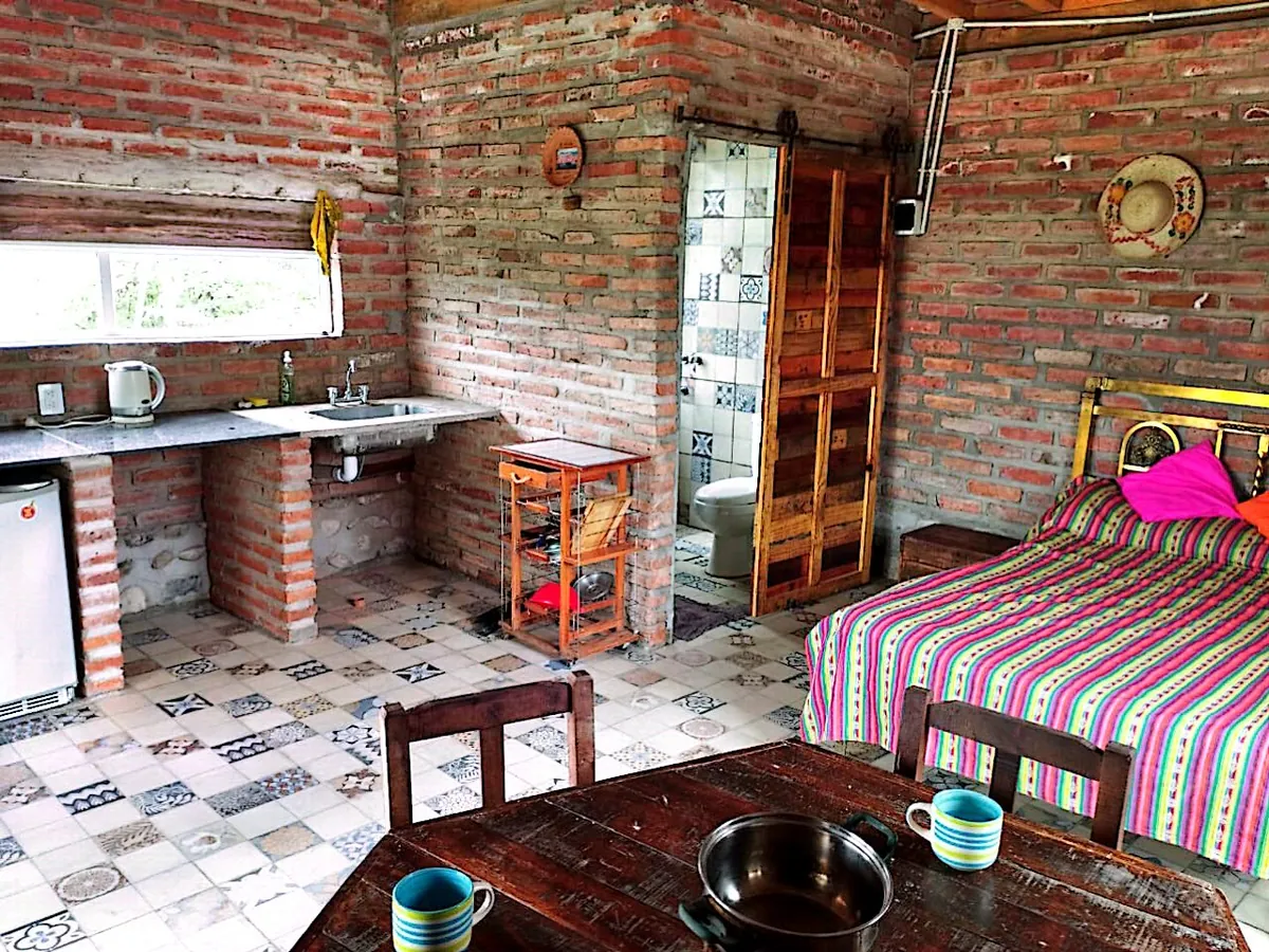 Interior de Ranchito: cama matrimonial, cocina y piso de baldosa calcárea